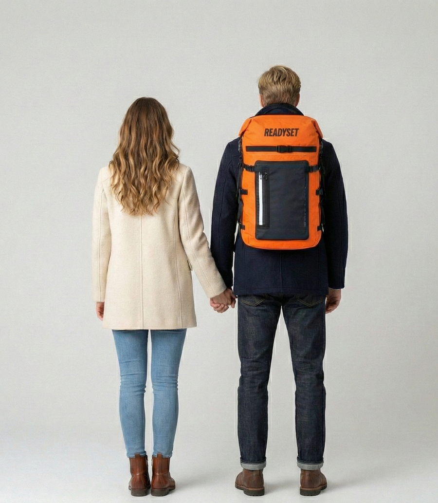 Two people holding hands, one with an orange backpack labeled 'ReadySet' on a plain background